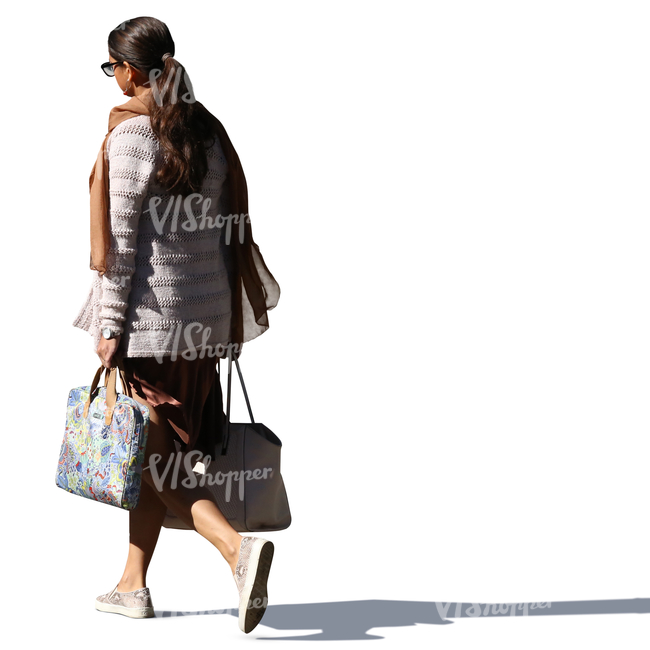 backlit woman walking and carrying two bags