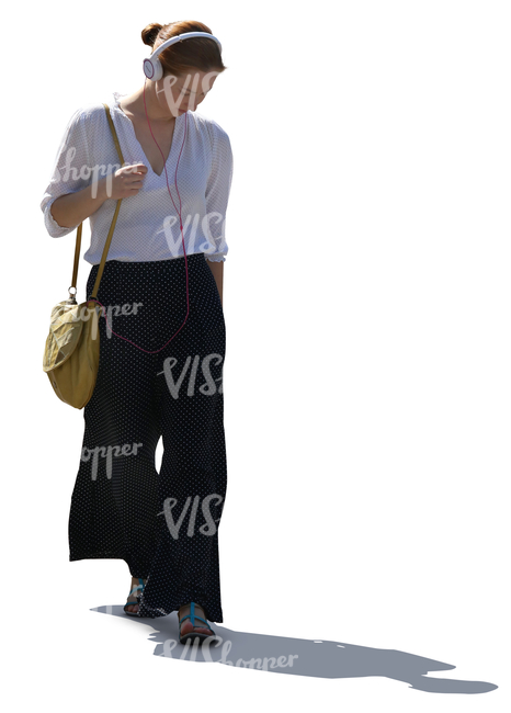 backlit woman with headphones walking and listening to music