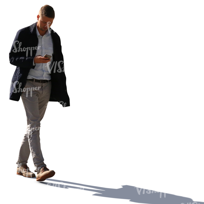 backlit man walking while looking at his phone