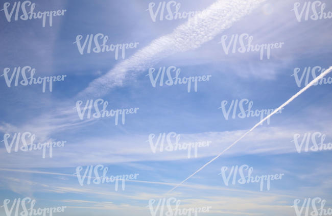 blue daytime sky with contrails and thin clouds