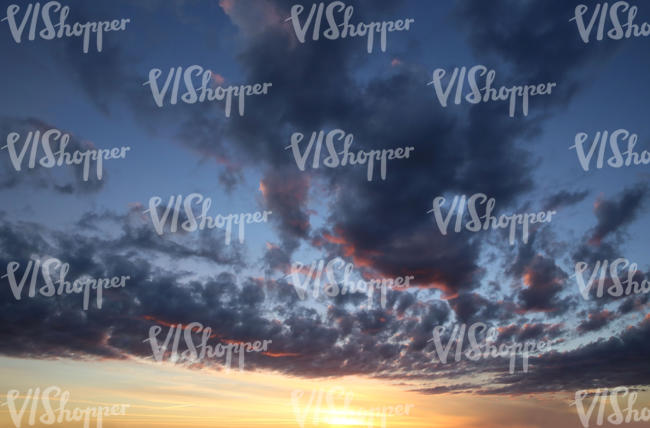 sunset with sun shining through dark blue clouds