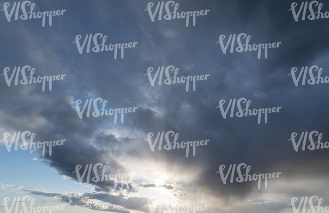 daytime sky with sun under the edge of grey cloud