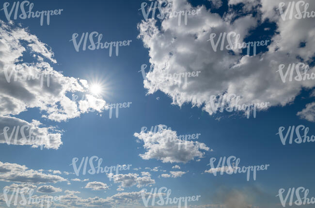 daytime sky with sun shining between white clouds