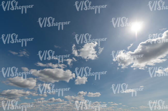 daytime sky with sun and small backlit clouds