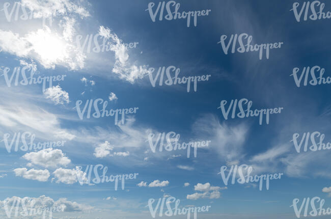 deep blue sky with sun and small clouds